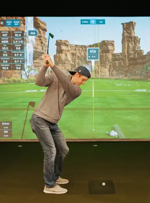 Man hitting golf ball into high quality impact screen with golf simulator setup